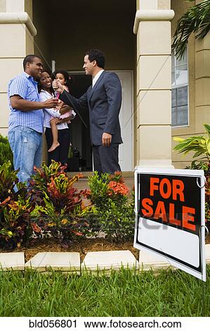 Hispanic real estate agent giving house keys to African family View Large Photo Image Stock Image - Hispanic real estate agent giving house keys to African family. Fotosearch