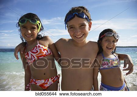 Picture - Hispanic siblings hugging at beach. Fotosearch