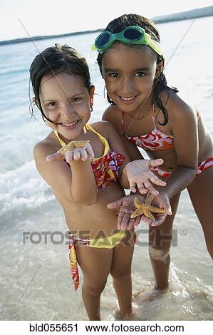 Stock Image - Hispanic sisters holding starfish. Fotosearch