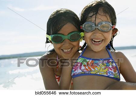 Stock Photograph - Hispanic sisters wearing goggles at beach. Fotosearch