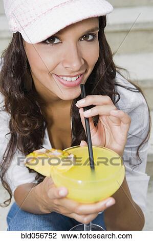 Stock Image - Hispanic woman drinking cocktail. Fotosearch