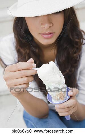 Stock Image - Hispanic woman eating ice cream cone. Fotosearch