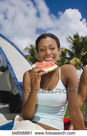 Stock Image - Hispanic woman eating watermelon. Fotosearch
