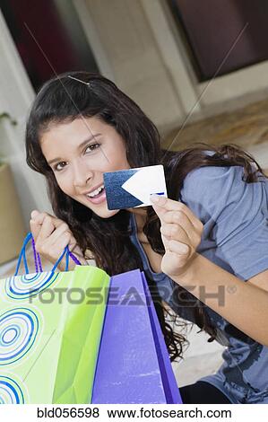 Stock Photo - Hispanic woman holding credit card and shopping bags. Fotosearch