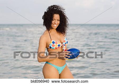 Stock Image - Hispanic woman in bikini holding football. Fotosearch