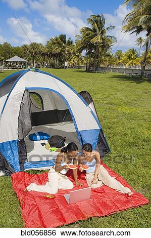 Stock Photograph - Hispanic woman looking at laptop in front of tent. Fotosearch