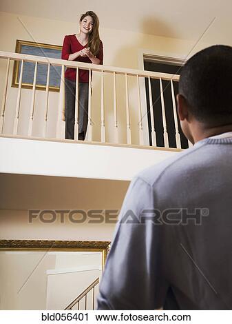 Stock Image - Hispanic woman looking down at boyfriend. Fotosearch