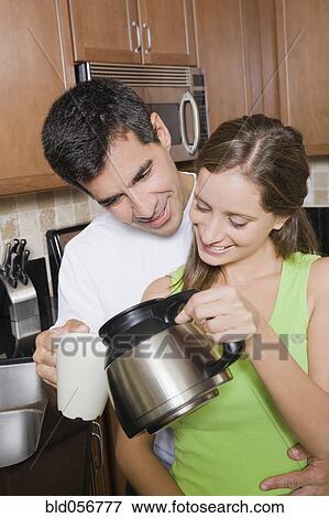 Stock Photo - Hispanic woman pouring coffee for husband. Fotosearch