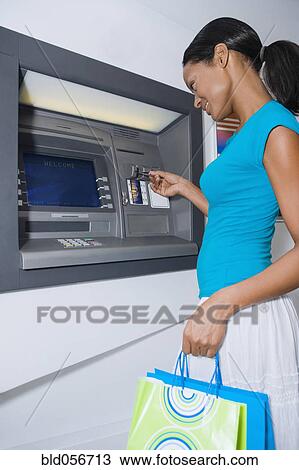 Stock Image - Hispanic woman using atm. Fotosearch