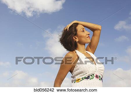 Stock Image - Hispanic woman with hand in hair. Fotosearch