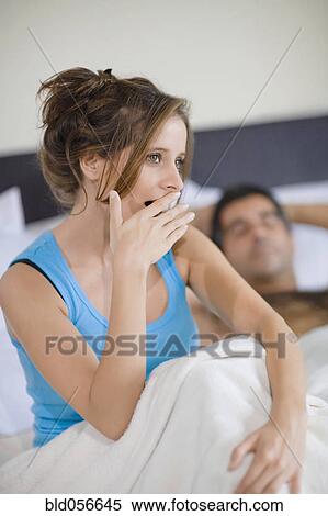 Stock Photography - Hispanic woman yawning in bed. Fotosearch