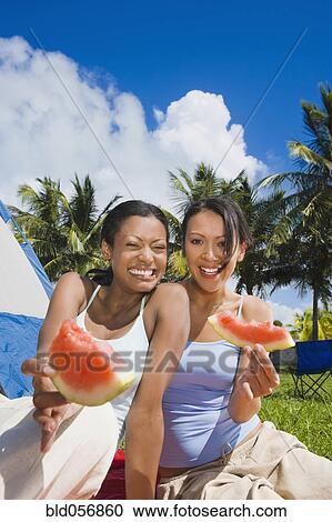 Stock Image - Hispanic women eating watermelon. Fotosearch