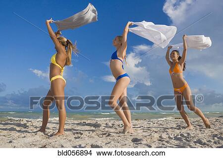 Picture - Hispanic women in bikinis holding skirts in wind. Fotosearch