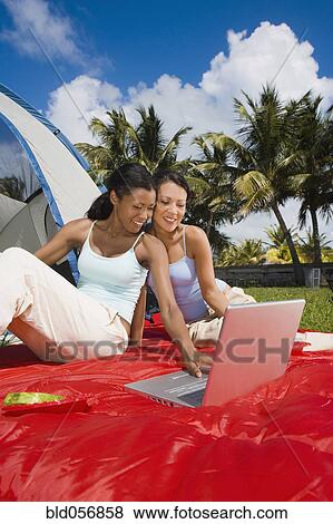 Stock Photo - Hispanic women looking at laptop. Fotosearch