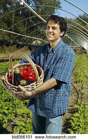 Stock Image - Man holding basket of organic produce. Fotosearch