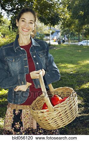 Stock Image - Middle Eastern woman carrying basket of organic produce. Fotosearch