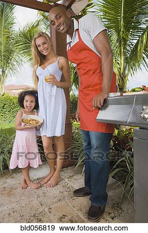 Stock Photo - Mixed Race family barbecuing. Fotosearch