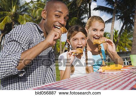 Mixed Race family eating at picnic table View Large Photo Image Stock Photo - Mixed Race family eating at picnic table. Fotosearch