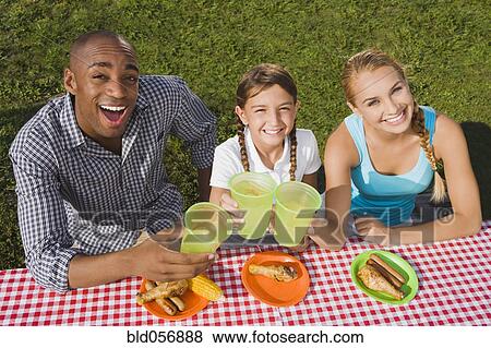 Mixed Race family toasting at picnic table View Large Photo Image Stock Photo - Mixed Race family toasting at picnic table. Fotosearch