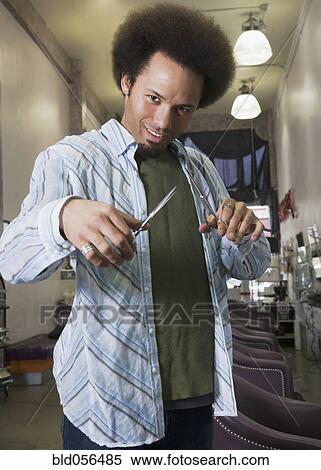 Stock Photography - Mixed Race male hair stylist holding scissors. Fotosearch