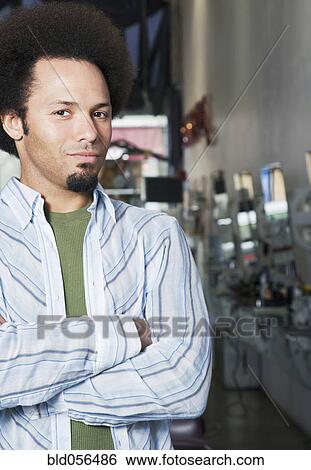 Stock Photograph - Mixed Race male hair stylist with arms crossed. Fotosearch