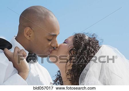 Stock Photo - Multi-ethnic bride and groom kissing. Fotosearch