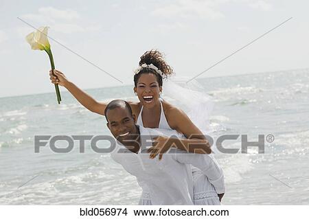 Multi-ethnic bride and groom playing at beach View Large Photo Image Picture - Multi-ethnic bride and groom playing at beach. Fotosearch