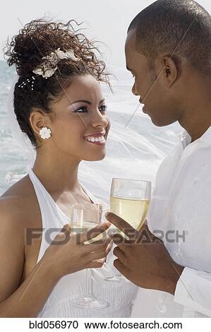 Stock Image - Multi-ethnic bride and groom smiling at each other. Fotosearch