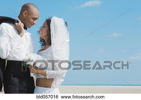Multi-ethnic bride and groom smiling at each other View Large Photo Image Stock Photograph - Multi-ethnic bride and groom smiling at each other. Fotosearch