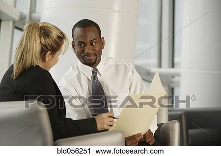 Stock Image - Multi-ethnic businesspeople discussing paperwork. Fotosearch