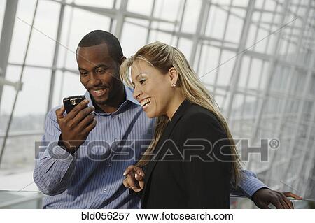 Stock Photo - Multi-ethnic businesspeople looking at cell phone. Fotosearch