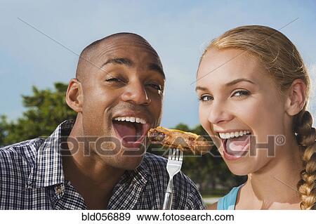 Stock Photo - Multi-ethnic couple eating from same fork. Fotosearch