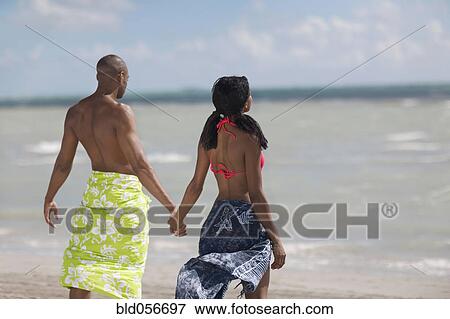 Multi-ethnic couple holding hands at beach View Large Photo Image Stock Photo - Multi-ethnic couple holding hands at beach. Fotosearch