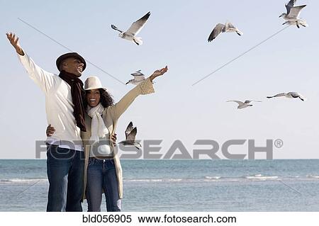 Stock Photography - Multi-ethnic couple hugging at beach. Fotosearch