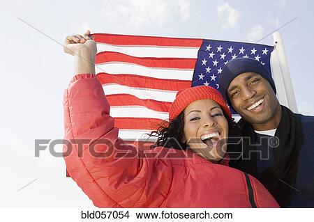 Picture - Multi-ethnic couple in front of American flag. Fotosearch