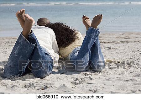 Multi-ethnic couple laying on beach View Large Photo Image Stock Image - Multi-ethnic couple laying on beach. Fotosearch