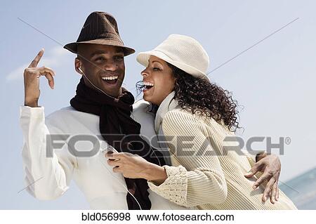 Stock Photo - Multi-ethnic couple listening to mp3 same player. Fotosearch