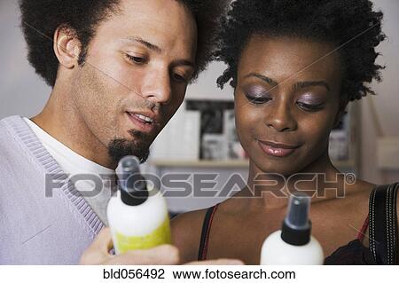 Stock Image - Multi-ethnic couple looking at hair product. Fotosearch