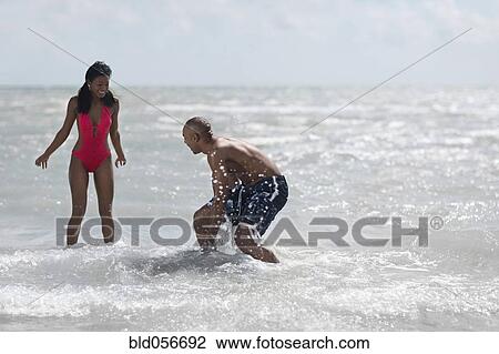Multi-ethnic couple playing in water View Large Photo Image Stock Image - Multi-ethnic couple playing in water. Fotosearch
