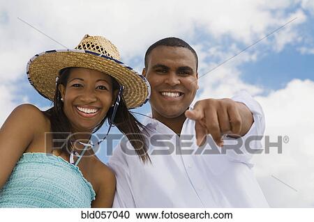 Stock Image - Multi-ethnic couple pointing and laughing. Fotosearch