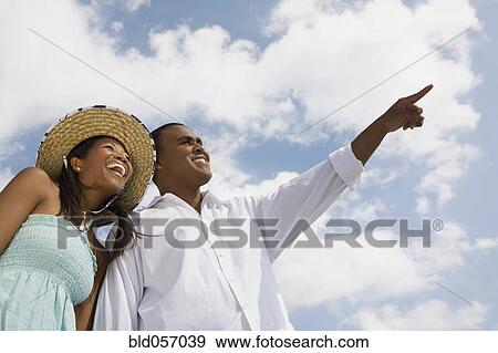 Stock Photo - Multi-ethnic couple pointing and laughing. Fotosearch