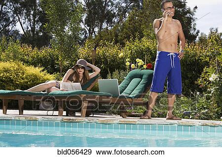 Multi-ethnic couple relaxing next to swimming pool View Large Photo Image Stock Photo - Multi-ethnic couple relaxing next to swimming pool. Fotosearch