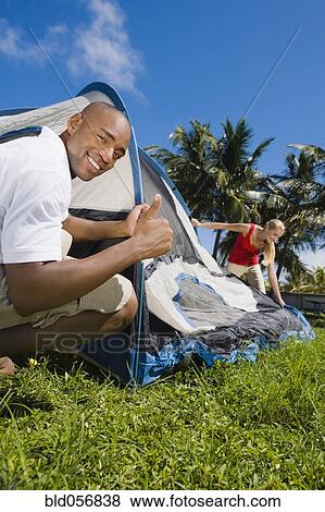 Stock Photo - Multi-ethnic couple setting up tent. Fotosearch