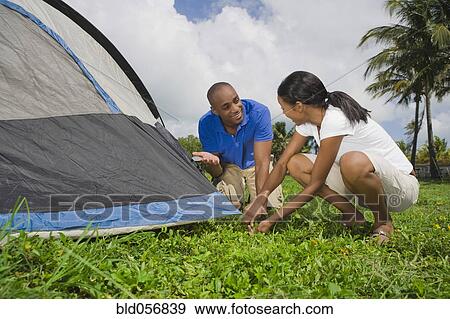 Multi-ethnic couple setting up tent View Large Photo Image Stock Photo - Multi-ethnic couple setting up tent. Fotosearch