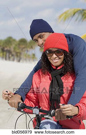 Stock Photo - Multi-ethnic couple sitting on bicycle. Fotosearch