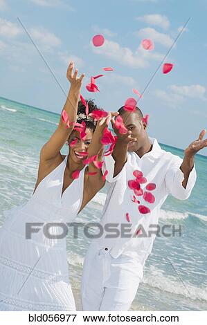 Stock Photo - Multi-ethnic couple throwing flower petals in air. Fotosearch