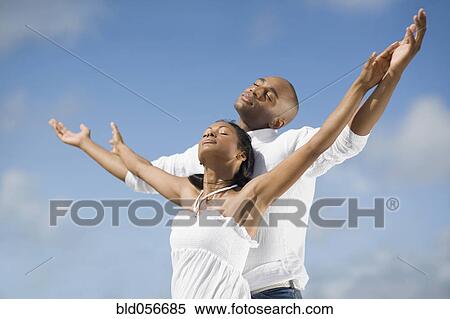 Multi-ethnic couple with arms raised View Large Photo Image Stock Photography - Multi-ethnic couple with arms raised. Fotosearch