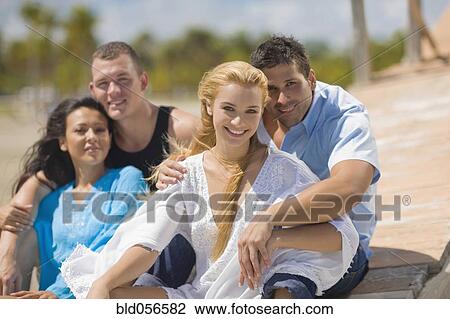 Stock Image - Multi-ethnic couples hugging at beach. Fotosearch
