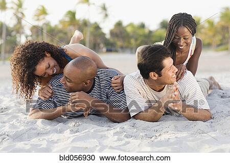 Multi-ethnic couples laying on beach View Large Photo Image Stock Image - Multi-ethnic couples laying on beach. Fotosearch