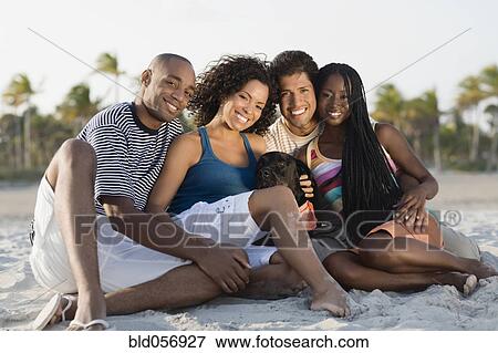 Multi-ethnic couples sitting on beach View Large Photo Image Stock Photo - Multi-ethnic couples sitting on beach. Fotosearch